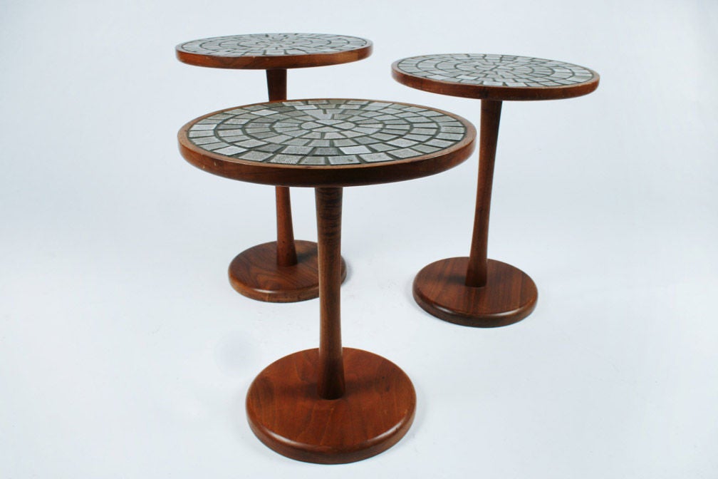 A group of three nesting tables each with solid walnut pedestal tulip bases and ceramic tile tops. Dimensions as shown 18 H 19 H 20 H x 13.25 diameter. By Jane and Gordon Martz for Marshall Studios. U.S.A. circa 1950.