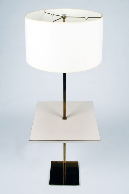 A floor lamp comprising a polished brass square tube pole with a square laminated tabletop attached to the mid-section; all mounted to a solid brass square footed base. Mod. no. 212FS by Stewart Ross James for Hansen, NYC. U.S.A., circa 1950.