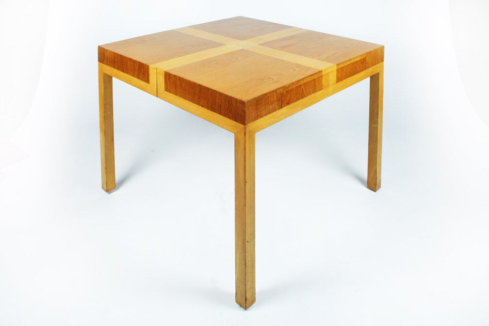 A rare and wonderful game table in bleached and natural walnut with two drawers, one at either end, and resting on four square legs; expands with a single leaf into a dining table 60