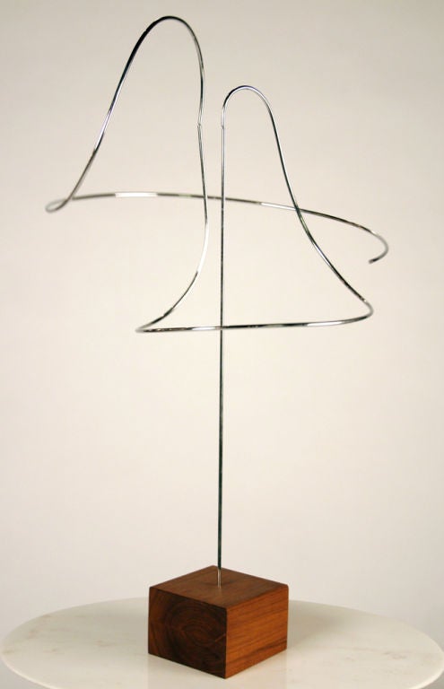 A fantastic kinetic sculpture comprising three steel stems: one straight supporting two asymmetrically curved elements that balance and swing delicately on pivot points; all supported on a wooden block stand. With hand written paper label to the