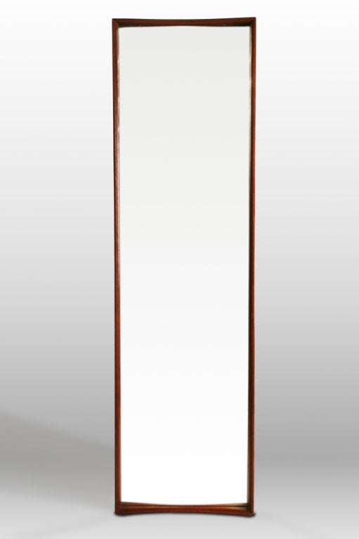 A tall and slender mirror in with a shadowbox sculpted teak wood frame. With paper label to the back. By AB Glas and Trä. Sweden, circa 1960.