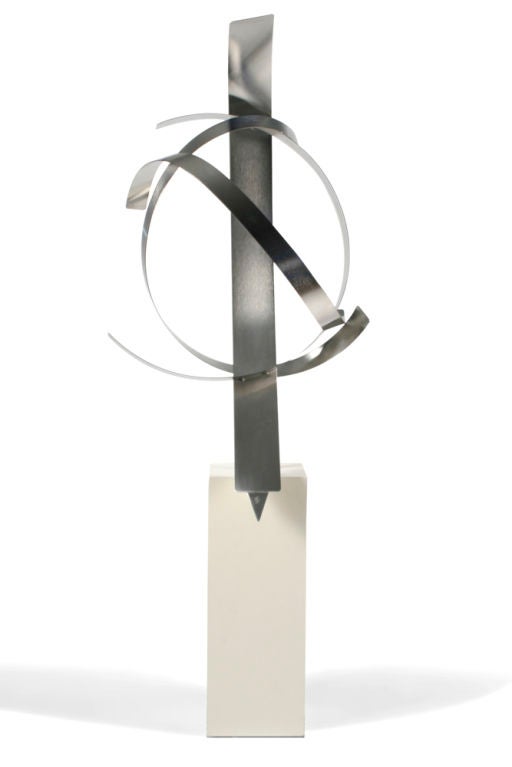 A tall abstract sculpture comprising four intertwined, sweeping strips of stainless steel, mounted on a square wood column base.  Signed “GB” to the tip.  American, circa 1960.
