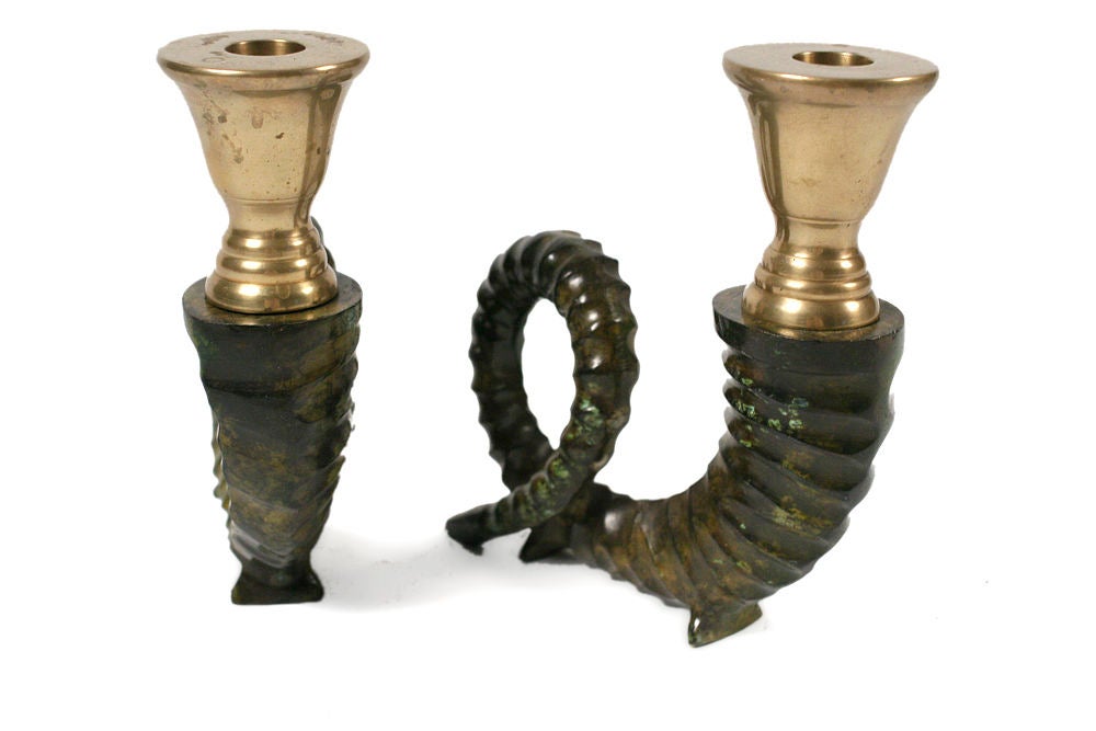 A wonderful pair of candlesticks in brass ram horn forms, with a wonderful bronze green patina.  By Chapman. American, circa 1970.