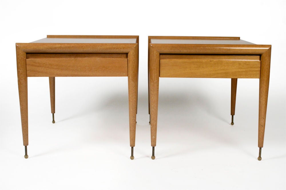 A wonderful pair of bleached mahogany side tables in a rectangular form with one drawer and a bullnose edged detail to the tabletop’s front and back that connect to the tapered legs with brass ball feet. With a maker’s stamp to interior of drawer.