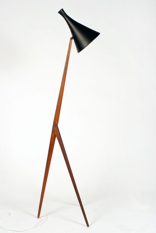 A mod floor lamp with a black enameled metal conical shade and a teak tripod stand. By Luxus, Swedish, 1960.
Measures: 55.75
