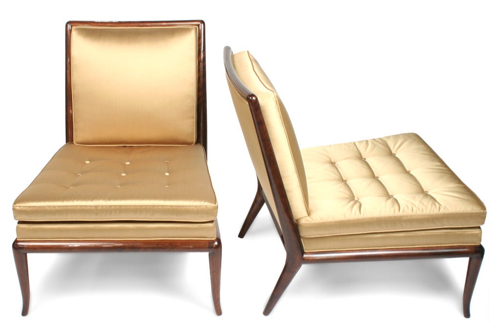 An exquisite set comprising two slipper chairs mod. no. WMB and an ottoman mod. no. WWA-6, each in a walnut frame and newly upholstered in a gold colored silk blend fabric. By T.H. Robsjohn-Gibbings for Widdicomb Furniture Company. U.S.A., circa