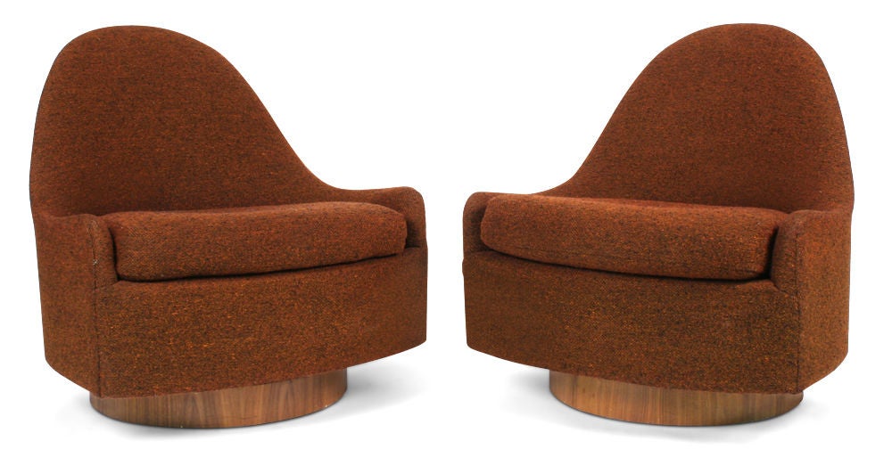 A pair of armless slipper chairs in a teardrop form that swivel and tilt and rest on circular, walnut veneer bases. By Milo Baughman for Thayer Coggin. American, circa 1970.