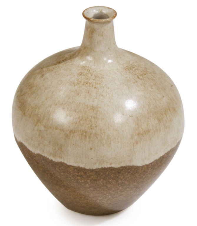 A ceramic bud vase having a thin lip, narrow neck and bulbous body with a two-tone glaze in oatmeal and brown.  Stamped 