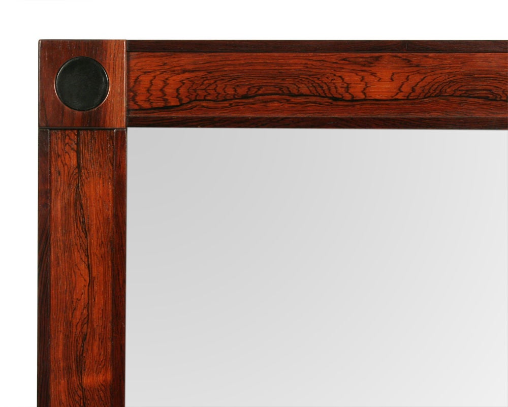 A large rectangular wall mirror in a beautiful rosewood frame with four leather roundels inset at each corner. Stamped to reverse [Made in Sweden]. Sweden, circa 1960.