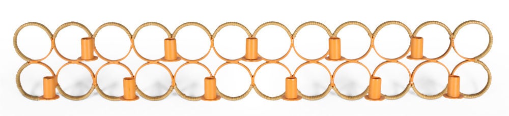 A rare wall-mounted candelabra comprised of two dozen orange lacquered wrought iron rings with rush twisted partially around each ring and eleven candles mounted on alternating rings. Designed by Arthur Umanoff for Raymor, U.S.A., circa 1950.