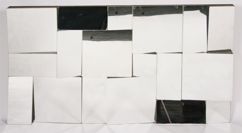 A rare vintage 'Slopes' wall sculpture comprised of faceted mirrored panels each at a different angle: upwards, downwards, to the left or to the right - never straight on.  By Neal Small.  American, circa 1970.