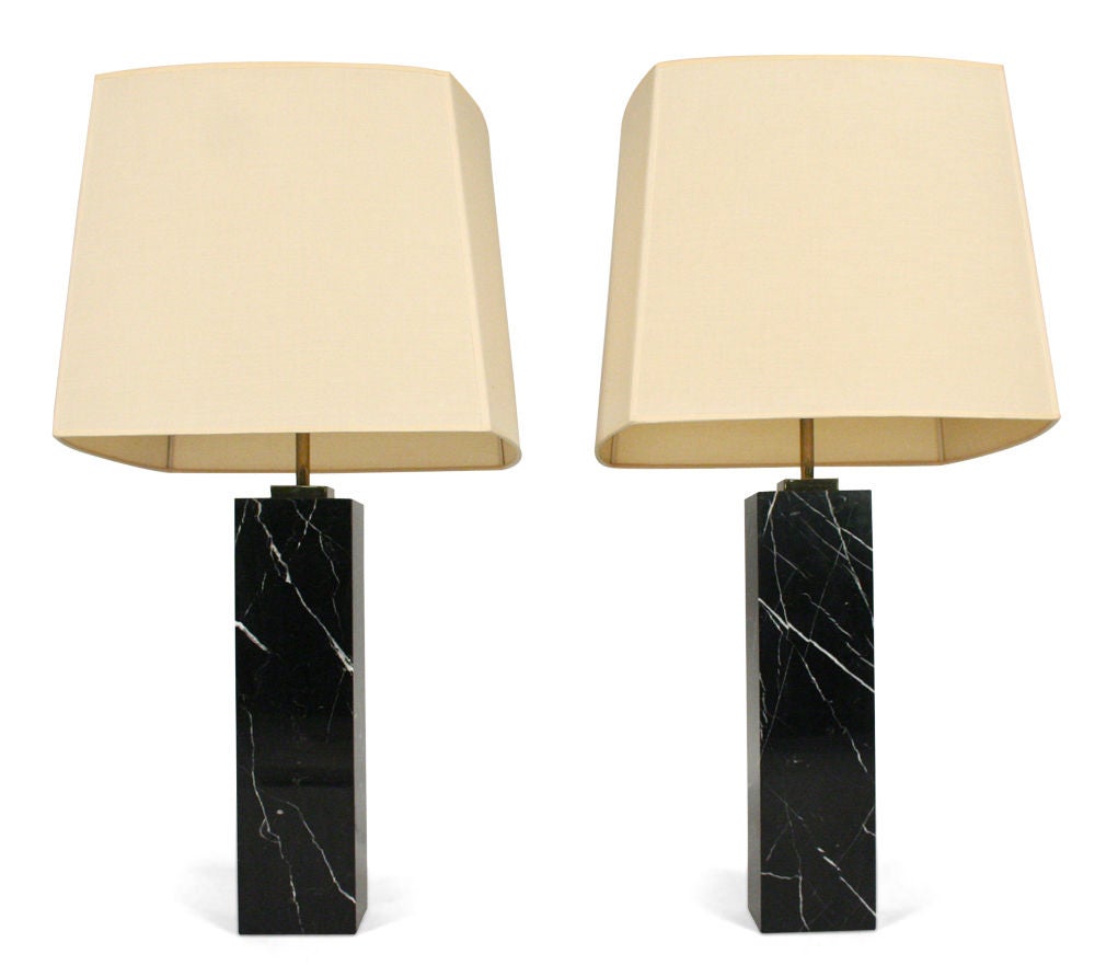 A pair of elegant column formed table lamps with polished brass risers and fittings extending into an exquisite black Marquina marble body each with their own unique sumptuous white veining throughout. Designed by T.H. Robsjohn-Gibbings for Hansen.