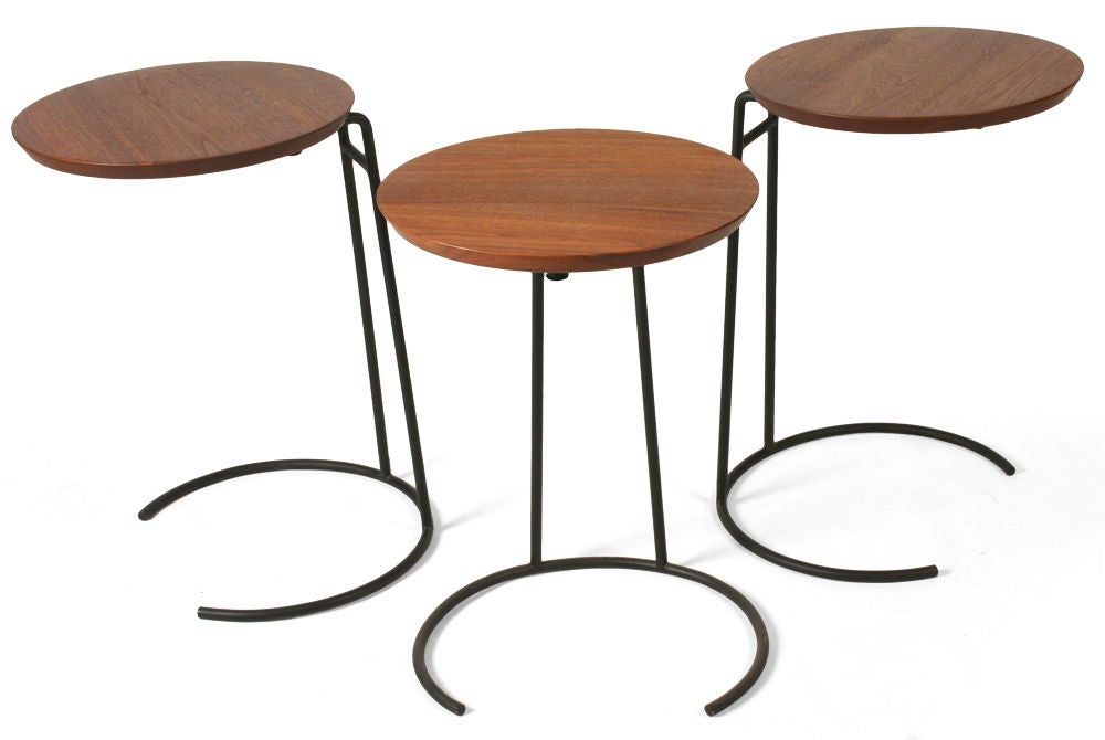 A clever set of stacking tables comprising circular knife-edge tops cantilevered on black enameled wrought iron bases. Model T. 710. With partial maker's label to the base. Designed by Jens Risom. U.S.A., circa 1950.