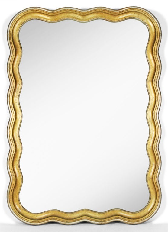 A sinuous mirror in an undulating carved wood frame with a gilded finish. American, circa 1950.