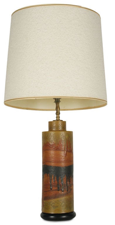 A round column shaped ceramic table lamp on a wood base with a painterly drip glaze body reminiscent of a desert landscape in colors of sandy yellow, burnt sienna, and charcoal. By Marcello Fantoni, Italy, circa 1950.
