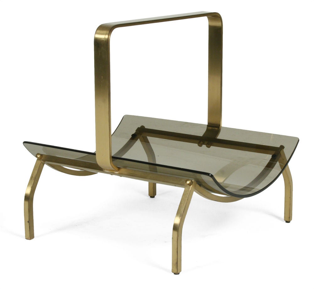 A chic magazine stand comprising a curved smoked glass shelf held within a bronze frame with an integral handle.  By Fontana Arte. Italian, circa 1960.