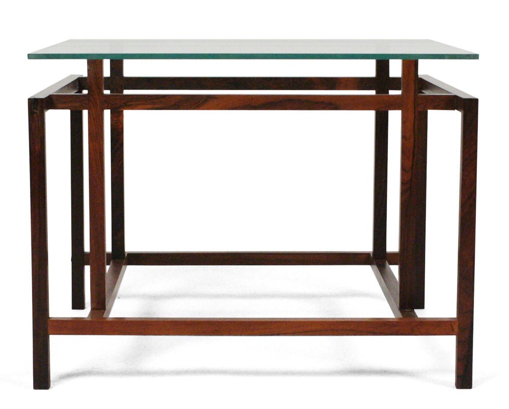 A pair of square cocktail tables with glass tops that fit the exact proportions of the elegantly engineered structures with tongue and groove joinery, nicely rendered in rosewood. By Komfort. Danish, circa 1960.