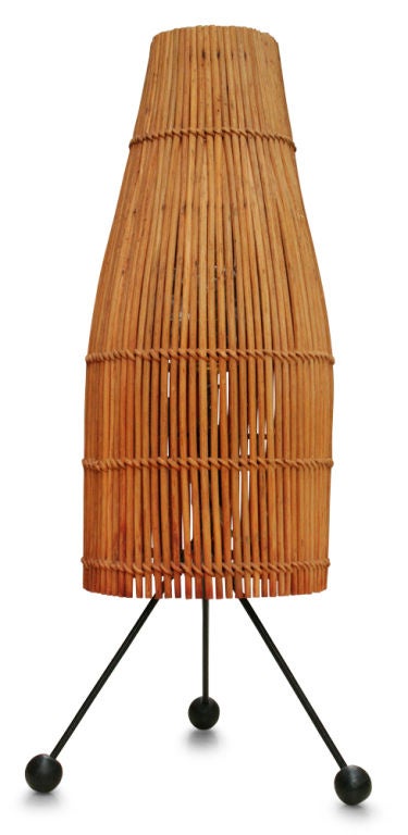 A mod pair of table lamps comprising wicker basket shades supported on a wrought iron tripod base with wood ball feet, American, circa 1950.