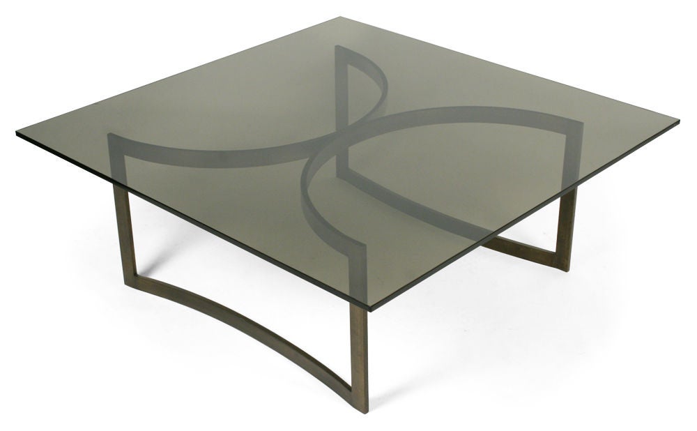 A fabulous cocktail table with a square smoked glass top resting on a bronze open frame base in a back-to-back demi-lune form.  After Brueton.  American, circa 1970.