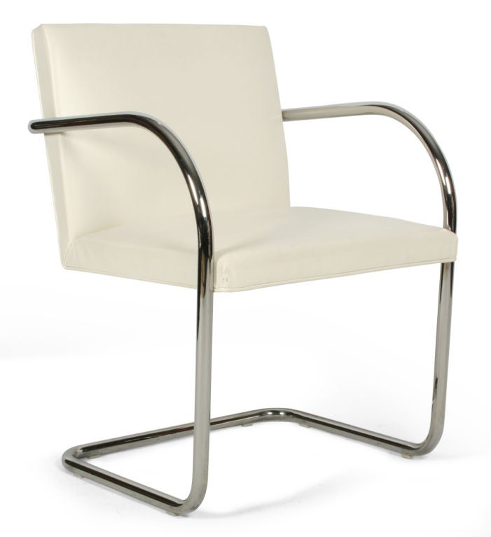 A classic International style armchair from the Brno collection designed by Ludwig Mies van der Rohe in 1930, comprised of a single piece of bent tubular chrome-plated steel as the frame supporting a white leather seat and back. With Knoll