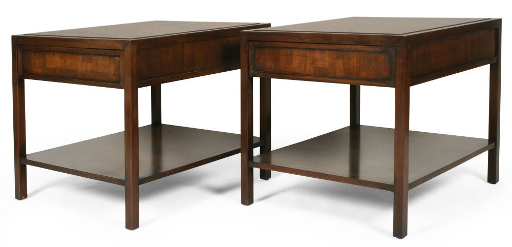 A pair of lamp end tables each comprising a single drawer with an inset parquet veneered drawer front, a rectangular tabletop with a slightly raised center, and a single lower shelf all within a rectangular wooden frame. With a John Stuart label to