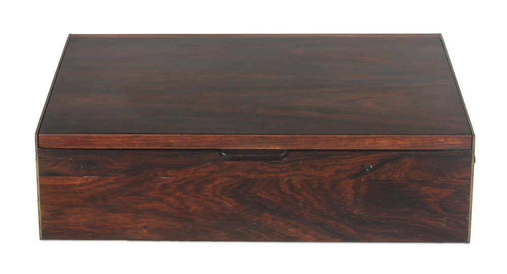 A refined jewelry box in rosewood comprising brass handles to the brass sides and hinges open to reveal three compartments and an inner mirrored lid. Danish, circa 1950.