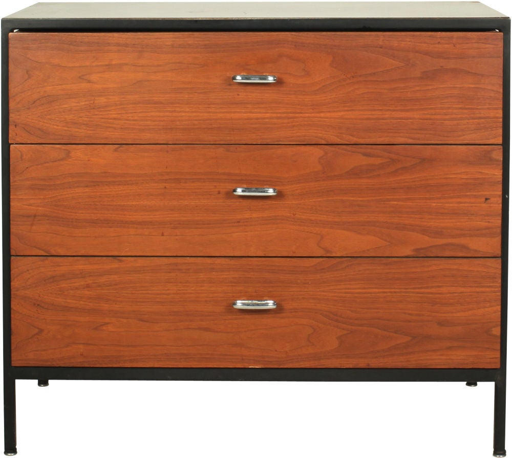A pair of Mid-Century Modern three-drawer chests with walnut veneered drawer fronts and elliptical chrome pulls, black enameled steel frames, orange lacquered sides and white laminate tops. From the 'steel frame' series by George Nelson for Herman