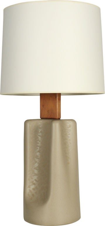 A bold table lamp comprising a square oiled walnut block neck and a broad pinched form body with an incised design to the concave section, all in a speckled oatmeal glaze. By Jane and Gordon Martz for Marshall Studios. U.S.A., circa 1960.

 