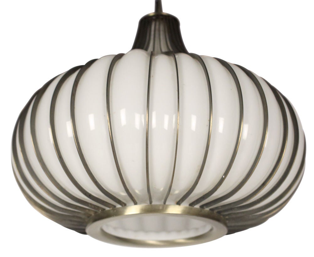 A Mid-Century Modern pendant light comprised of white handblown glass within a ribbed metal frame shaped like an onion. By Litecraft. U.S.A., circa 1970s.

 