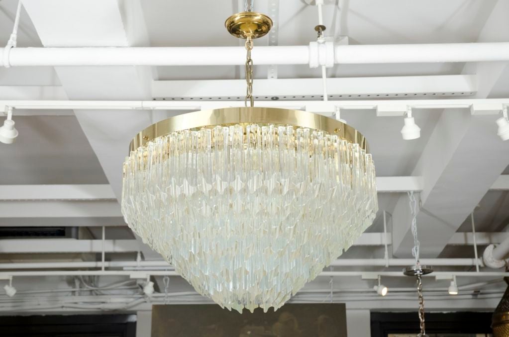 A sparkling chandelier with diamond shaped glass prism elements on a circular brass frame, stepping down to form an upside-down pyramid. By Camer Glass. Italy, circa 1960.