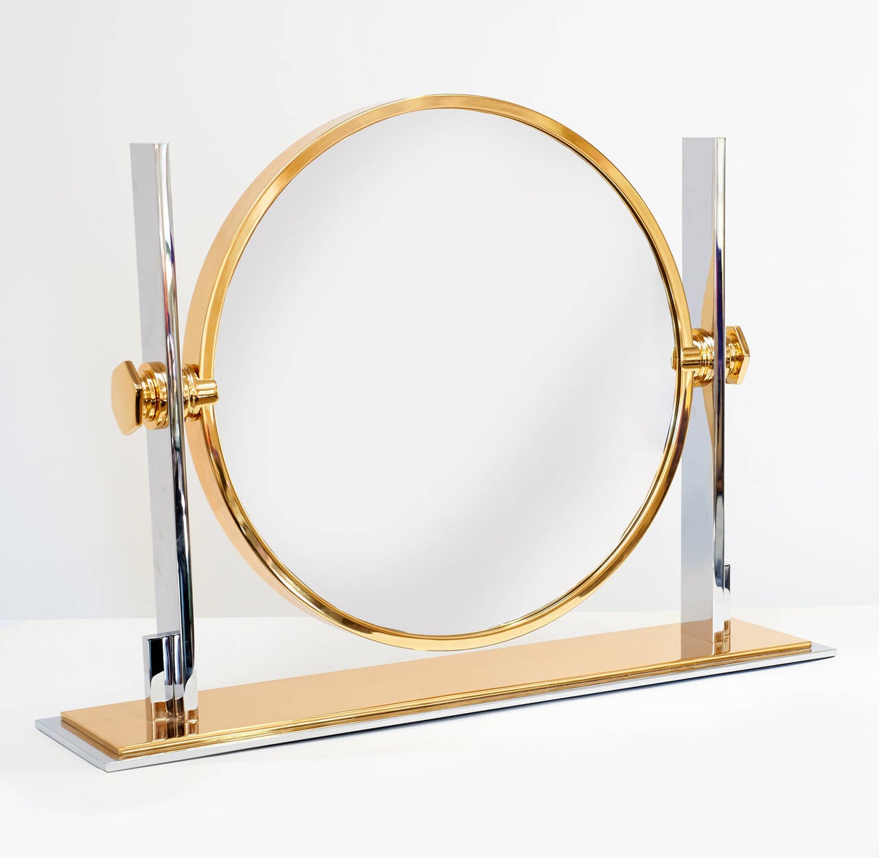 Precision crafted polished chrome and brass tabletop vanity mirror. Rotational frame holds standard and convex magnified mirrors. By Karl Springer, American, circa 1980. NYDC