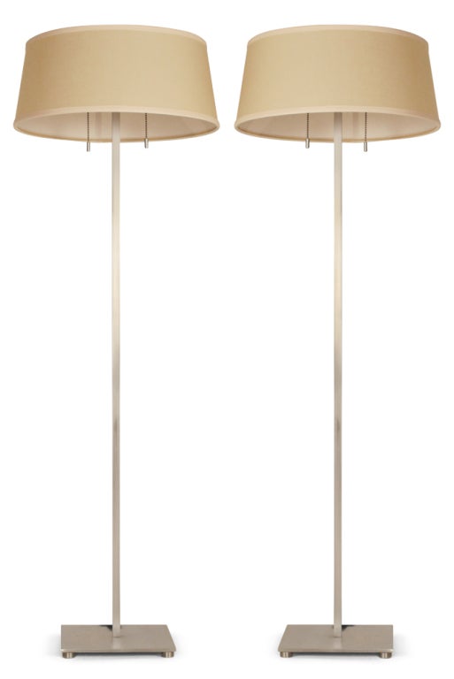 A pair of classic Modernist floor lamps comprising satin steel square tube stems mounted to a solid square footed base with double light sockets, pull chain switches and round white enameled diffusers. Mod. no. 212. By Stewart Ross James for Hansen,