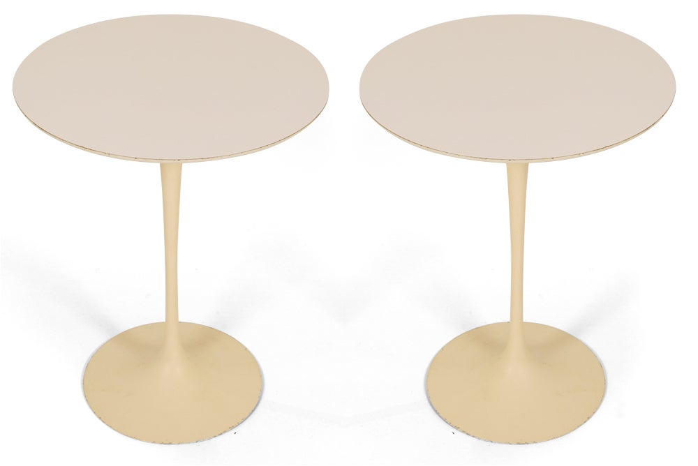 A vintage pair of classic Mid-Century Modern round 'tulip' side tables with white laminate tops supported on enameled cast iron pedestal bases. Model number 160 with manufacturer’s paper label to base. By Eero Saarinen for Knoll International.