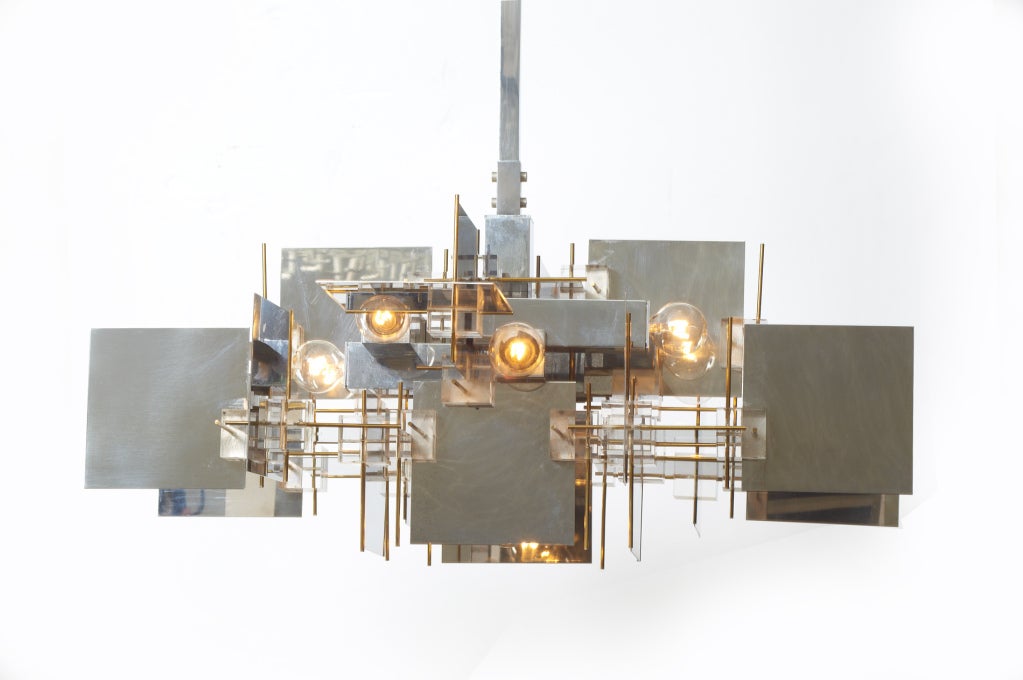 A fantastic multi-dimensional chandelier comprising polished chrome steel panels at varying axis with Lucite cube and brass pin accents.  By Gaetano Sciolari.  Italian, circa 1960.