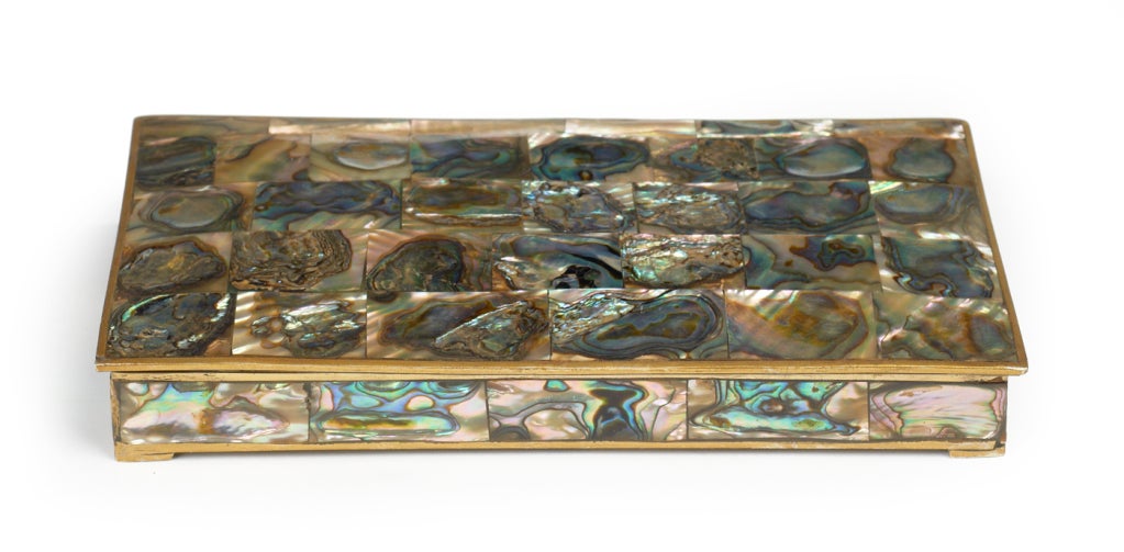 A lustruous keepsake or jewelry box in alpaca nickel and veneered with abalone shell tiles on the top of the hinged lid and around the box sides. Stamped to the base 