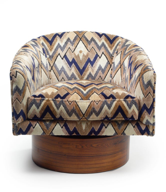 A pair of barrel back lounge chairs upholstered in original chevron-like patterned fabric raised on a tall round swivel plinth veneered in rosewood. By Milo Baughman for Thayer Coggin. American, circa 1970.