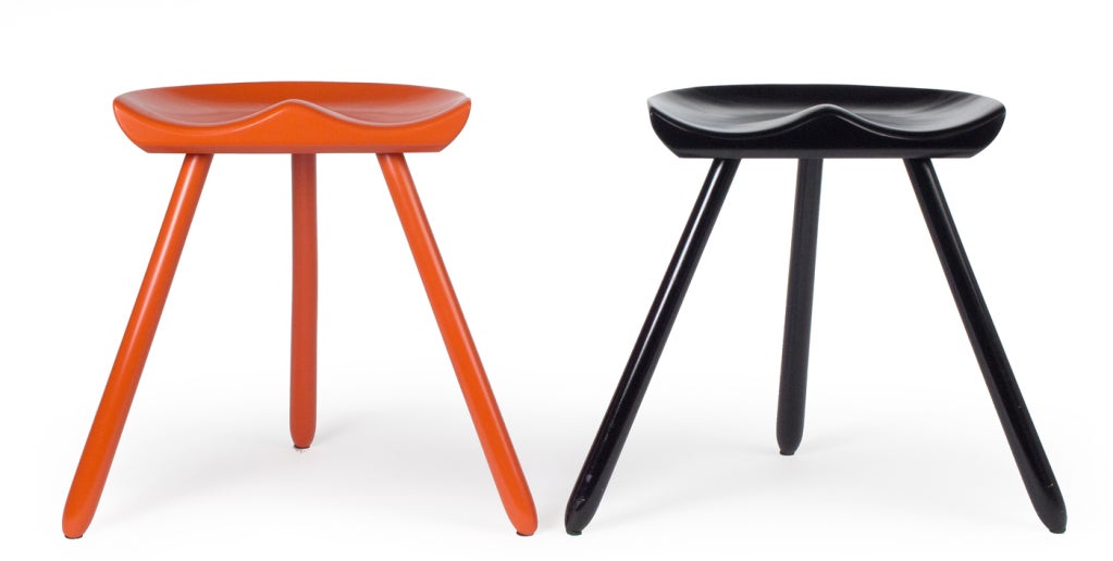 Milking stools with sculpted seats supported on three legs; one in orange and one in black lacquer. After a design by Mogens Lassen. By Arne Hovmand-Olsen. Denmark, circa 1950.

  