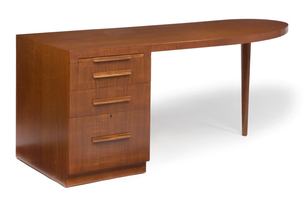 A rare writing desk with a curved wing top over a pedestal of three drawers and an oval tapered leg. By T.H. Robsjohn-Gibbings for Widdicomb. American, circa 1950.