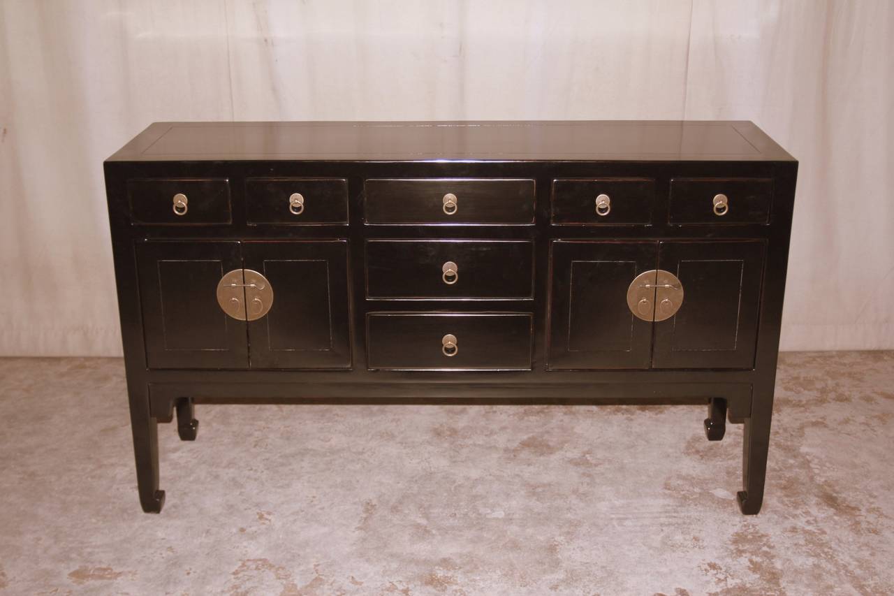 A refined and elegant black lacquer table, framed top supported by square legs and joined by seven drawers and two pairs of doors, brass fitting and ring pulls.