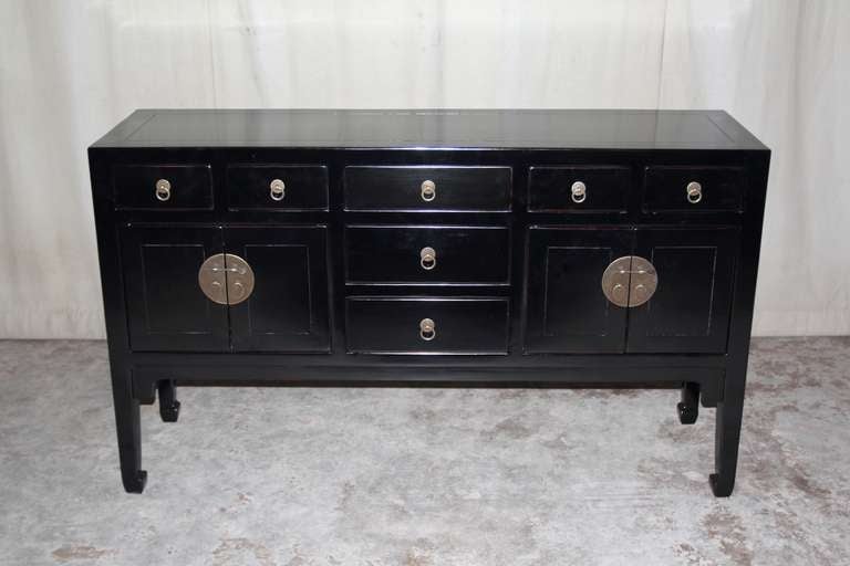 A refined and elegant black lacquer table, framed top supported by square legs and joined by seven drawers and two pairs of doors, brass fitting and ring pulls.