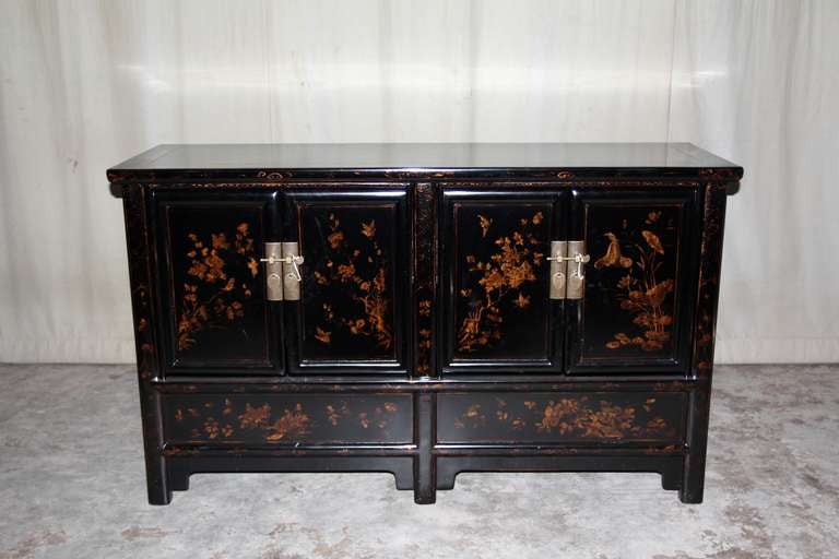 A very refined and elegant black lacquer sideboard with muted gold gilt floral motif on two pairs of doors, brass fitting.