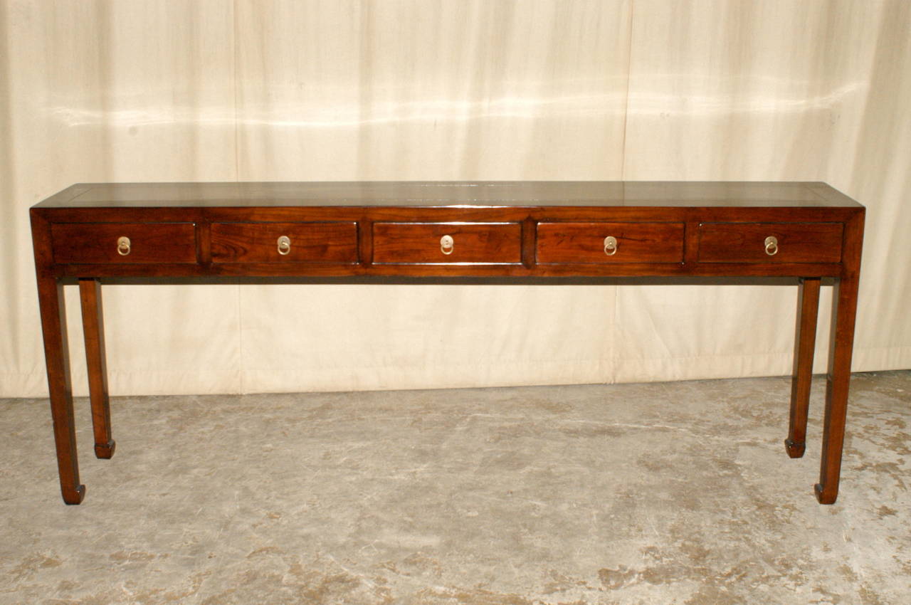 A refined and elegant ju mu wood console table with five drawers, brass ring pulls, beautiful color, form and lines.