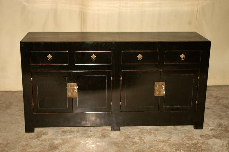 A refined and elegant black lacquer sideboard with four drawers on top of two pairs of doors, brass fitting, beautiful color, form and lines