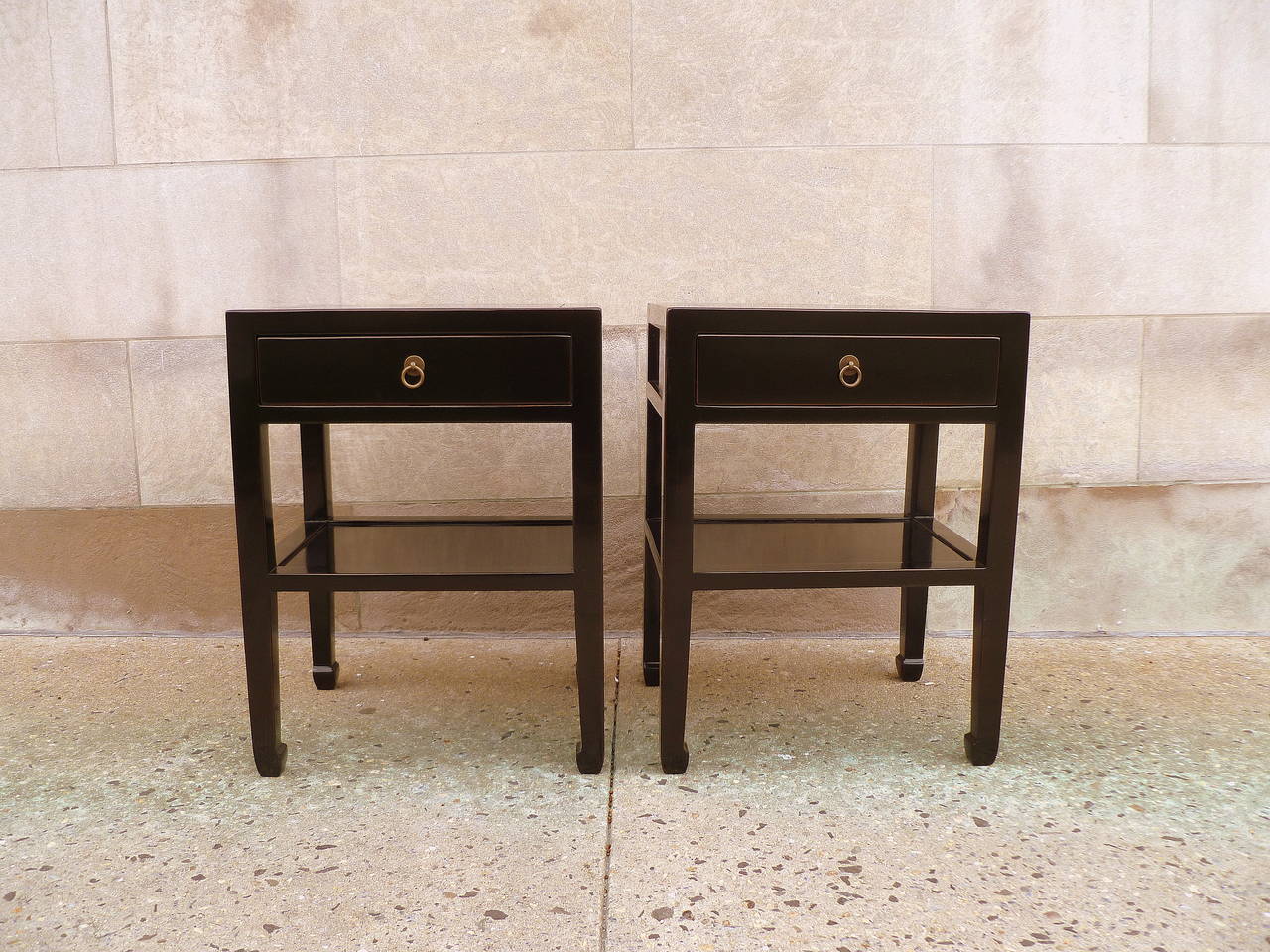 a pair of simple and refined black lacquer end tables, each with a drawer and a shelf, brass ring pulls, beautiful color, form and lines.