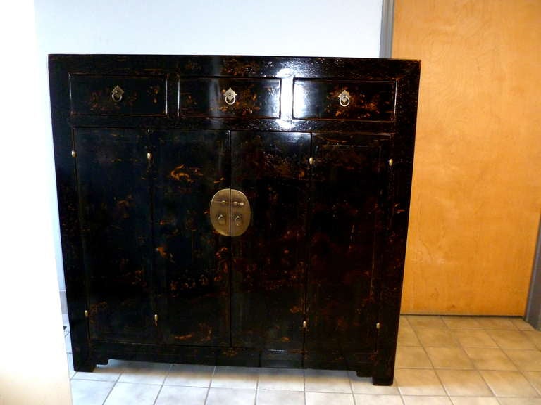 A refined and elegant black lacquer sideboard with hand painted gold gilt motif on the pair of bifold doors and three drawers, brass fitting, beautiful color, form and lines.