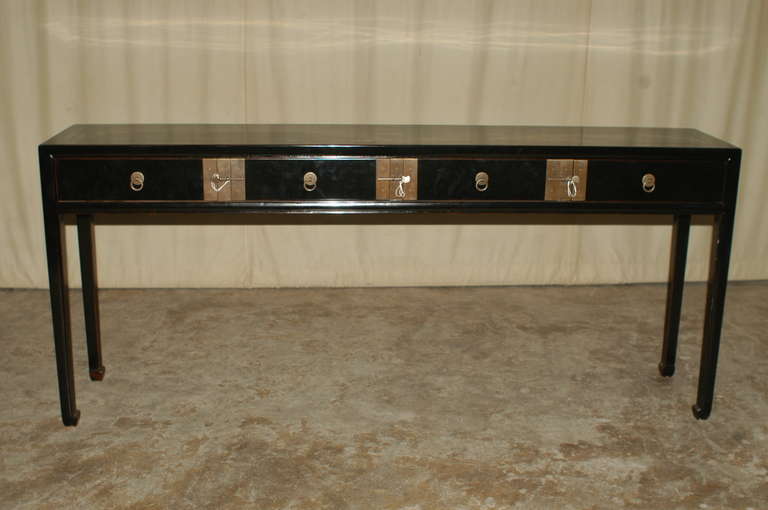 A simple and elegant black lacquer table with four drawers, brass ring pulls and locks. Beautiful form, lines and colors.