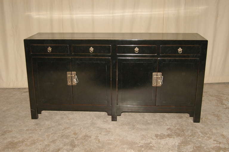 A refined and elegant black lacquer sideboard with four drawers on top of two pairs of doors, brass fitting, beautiful color, form and lines. 