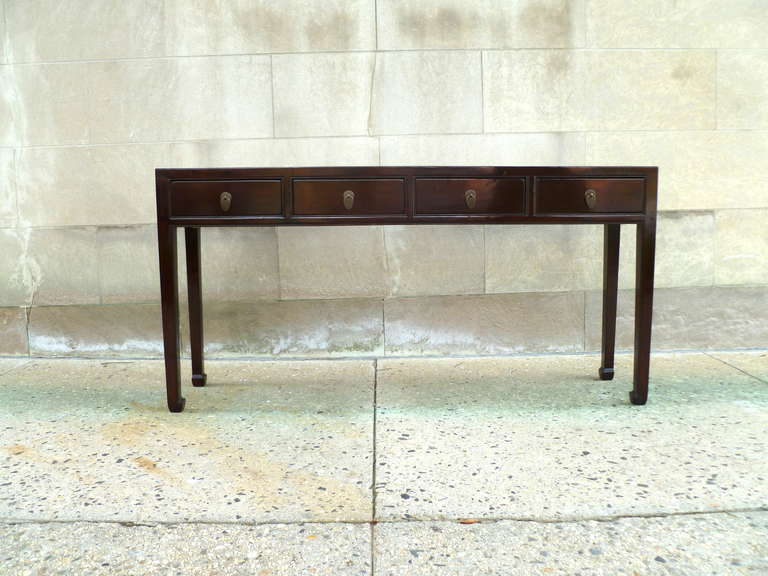 A refined and elegant ju mu wood table with four drawers, brass ring pulls, beautiful color, form and lines.