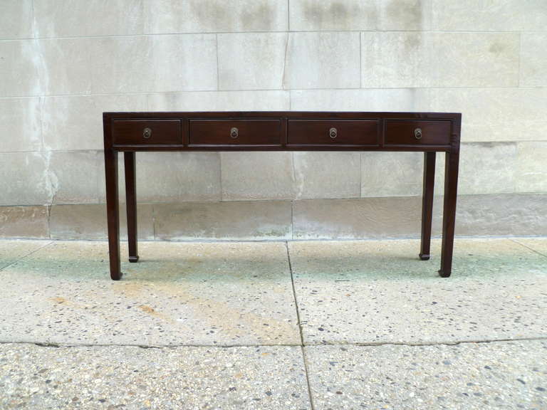 A refined and elegant ju mu wood table with four drawers, brass ring pulls, beautiful color, form and lines