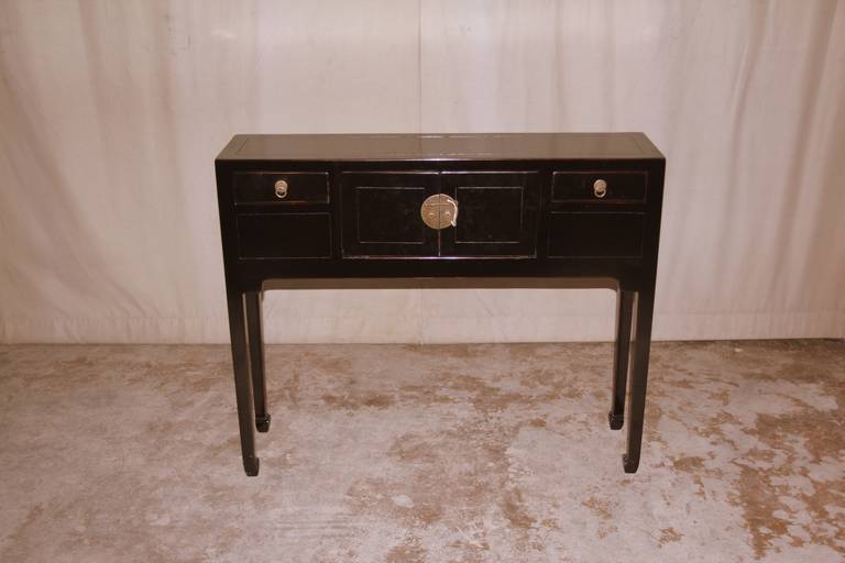 A simple and elegant black lacquer table, framed top supported by slender legs and joined by two drawers and a pair of doors, brass fitting, beautiful color and form.
